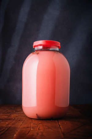 Jar of homemade bread and hibiscus kvass on wooden background. Traditional slavic beverage kvas, cold summer drink. Shadow patternの写真素材