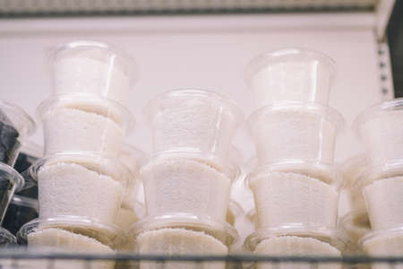 Coconut flakes in small plastic containers on shelf. Grocery department, food store, supermarket. Shopping ingredients for bakery, sweets.の写真素材