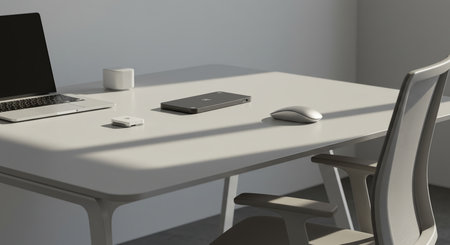 A clean, contemporary office desk setup featuring a laptop, smartphone, and computer mouse, illuminated by gentle natural light casting soft shadows.の素材
