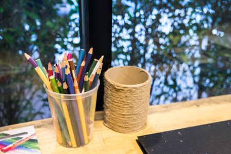 Crayons in a mug on a wooden table.の写真素材