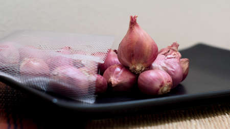 Red Onion on Black Plate on Wooden Table.