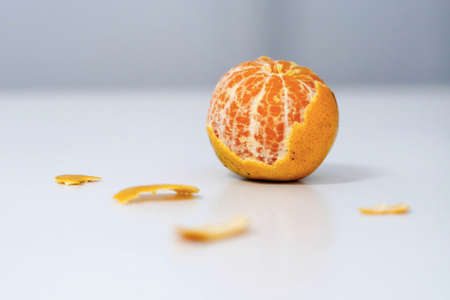 One fresh whole mandarin orange with leaf and one peeled and sectioned mandarin orange.の写真素材