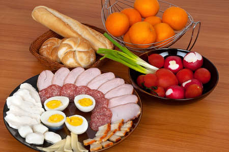 Rich breakfast containing vegetables, bacon, eggs, salami and bread