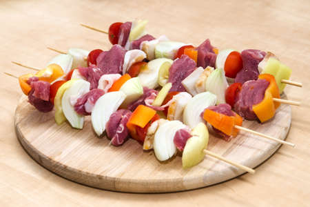 Meat and vegetables on skewers on wooden backgroundの写真素材