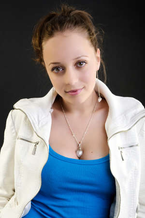 Girl with white jacket posing on dark backgroundの写真素材