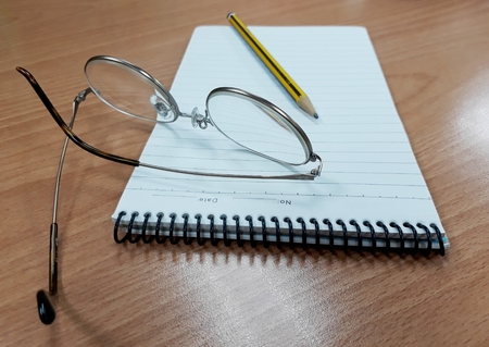 From a different view of the notebook, pencil and glassesの写真素材