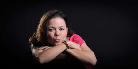 The girl in the red sitting on a chair. Black backgroundの写真素材