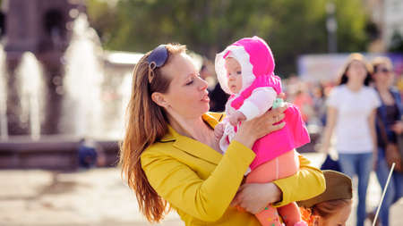 Mom keeps on hand a small child. A family walk in the spring in the Park. The woman in the yellow jacket. A blurred background.の写真素材