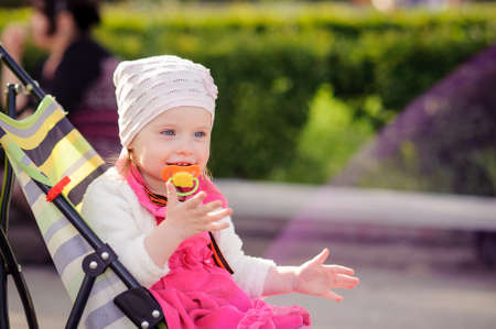Little girl sits in a wheelchair. The child smiles. A family walk in the spring in the Park. A...