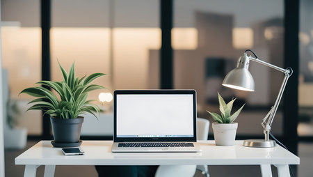 Close up of modern workplace with blank screen laptop, coffee cup and other items on white table in officeの素材
