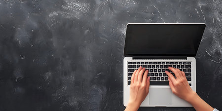 Top view of female hands typing on laptop keyboard on grey concrete backgroundの素材