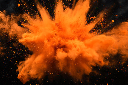 Explosion of orange powder, isolated on black background. Abstract backgroundの素材