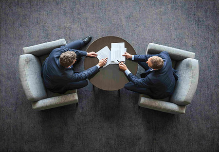 Top view of two businessmen sitting in armchairs and reading documents. Business conceptの素材