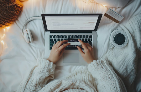 Cropped image of young woman using laptop and credit card on bedの素材
