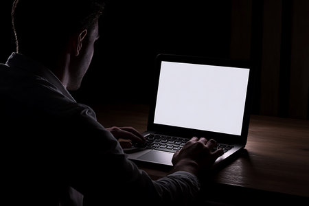 Silhouette of a man working with a laptop in the darkの写真素材