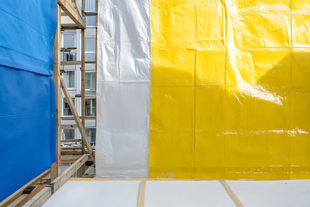 Construction site with scaffolding and yellow and blue sheets of a new houseの写真素材