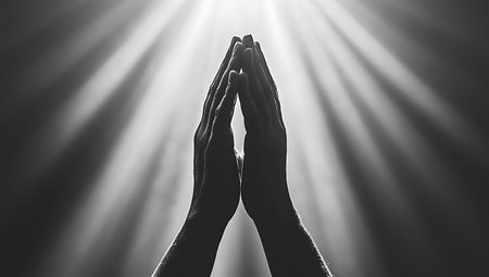 Silhouette of hands in prayer on white background with rays of lightの写真素材