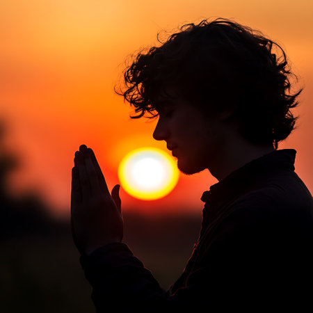 Silhouette of young man praying with beautiful sunset in the backgroundの写真素材