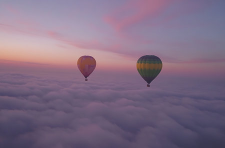 Hot air balloons flying over the clouds at sunset. Colorful sky.の写真素材