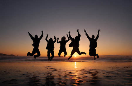 Silhouette of group of people jumping on the beach at sunsetの写真素材