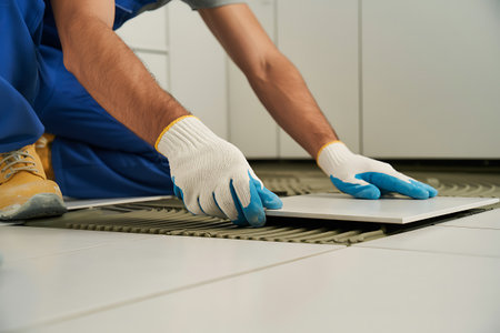 Worker installing ceramic tile on floor in kitchen, closeup viewの写真素材