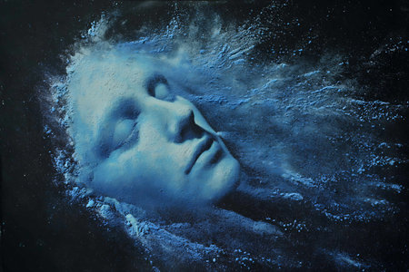 Portrait of a beautiful woman painted with blue paint on dark backgroundの写真素材