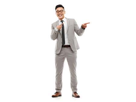 business, gesture and people concept - smiling asian businessman pointing finger to side over white backgroundの写真素材