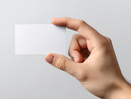 Hand holding blank business card on grey background, closeup. Mockup for designの写真素材