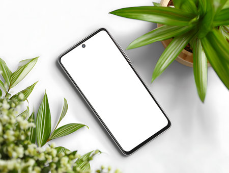 Smartphone mockup with blank screen and green plant on white backgroundの写真素材