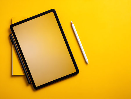 Tablet computer and pencil on yellow background. Top view with copy spaceの写真素材