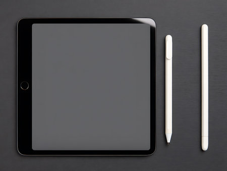 Tablet computer with blank screen and two white pencils on black backgroundの写真素材