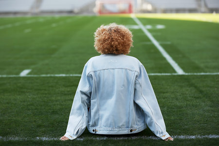 Rear view of african american woman sitting on football fieldの写真素材