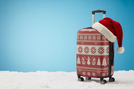 Travel suitcase with santa hat on blue background. Holiday concept.の写真素材