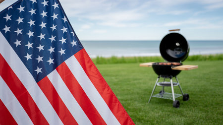 American flag and barbecue grill on the green grass by the sea.の写真素材