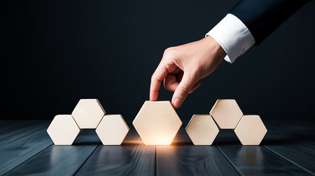 Close up of human hand arranging wooden hexagons as symbol of growthの写真素材