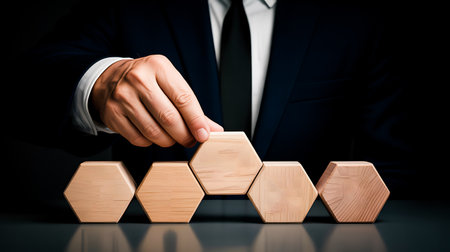 Businessman arranging wooden hexagons as a symbol of leadership and successの写真素材