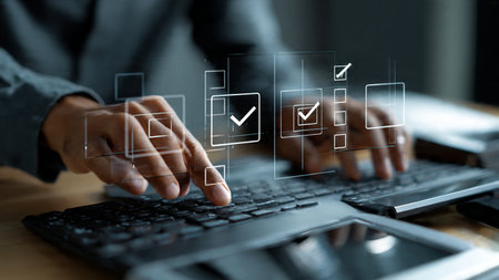 A businessman in a gray suit uses a laptop with digital checklists and to-do lists overlaid on the screen, indicating productivity and task management.の写真素材