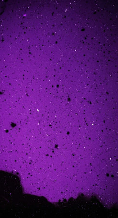 A vibrant purple night sky with stars and a dark landscapeの写真素材