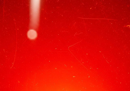 A vibrant red background with scratches and a bright lightの写真素材