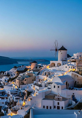 A picturesque Greek village with whitewashed houses and windmills at dusk overlooking the oceanの写真素材