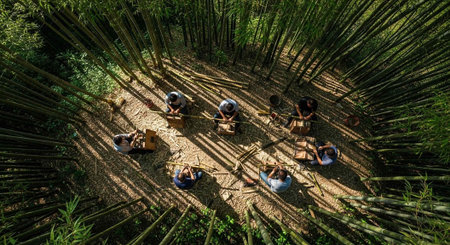 A group of people sitting in a circle on the ground in a bamboo forest surrounded by greeneryの写真素材