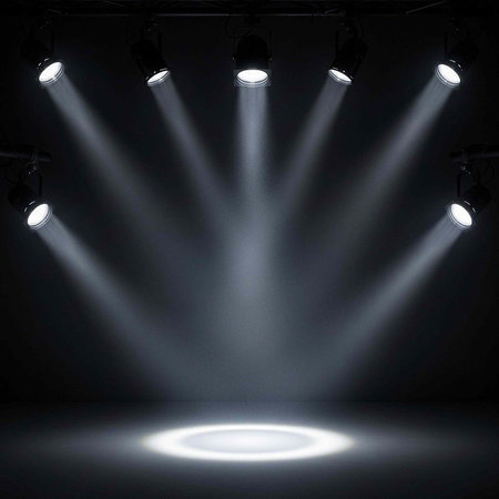 A dramatic stage lit by multiple spotlights shining down from above in a dark roomの写真素材