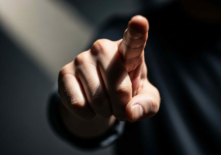 A person's hand is shown with the middle finger extended, illuminated by a light sourceの写真素材