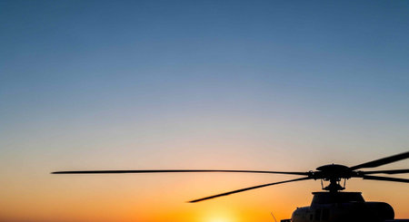 Helicopter silhouette at sunset with bright orange and blue gradient skyの素材