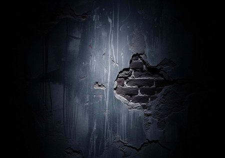 A dark and mysterious space with a small opening in the wall revealing a glimpse of lightの写真素材