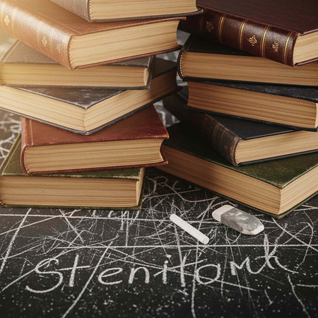 A stack of books and a piece of chalk on a blackboard with scribbles and a word written in chalkの写真素材