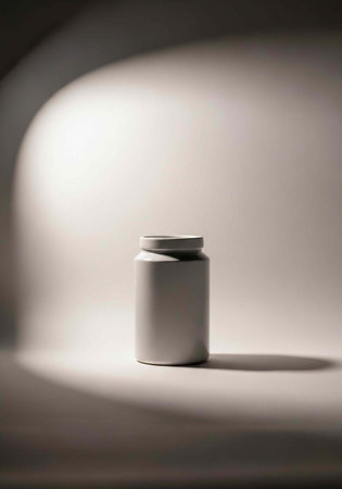 A white plastic bottle stands alone on a gray surface, illuminated by a spotlight with a distinct shadowの写真素材