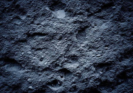 Close-up of dark blue gray stone surface with rough texture, bumps, and holes, showcasing natural ruggedness and detailの写真素材