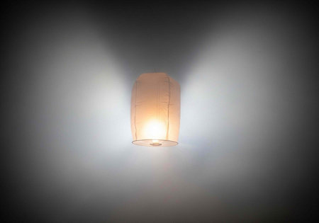 A glowing paper lantern emits warm light against a dark backgroundの写真素材