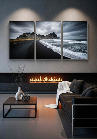A sleek, modern living room featuring a black leather sofa, minimalist coffee table, and a large triptych landscape artwork above a fireplaceの写真素材